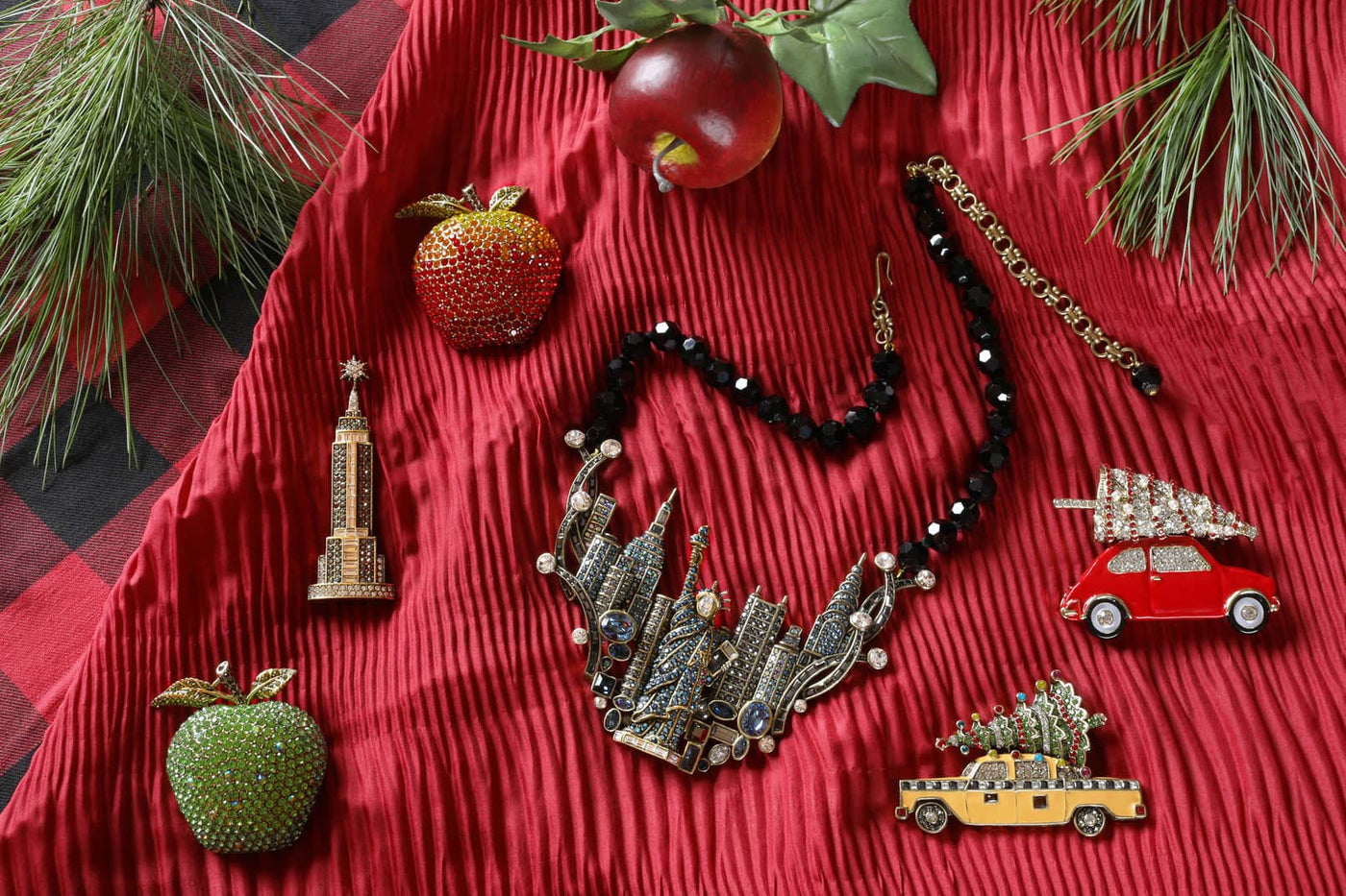 Necklace with decorative pendants on a red textured surface with Christmas-themed items.