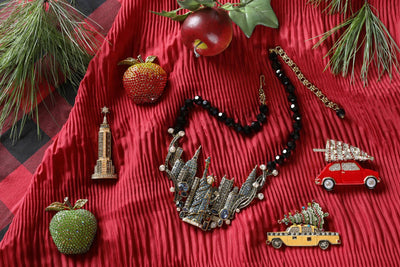 Necklace with decorative pendants on a red textured surface with Christmas-themed items.