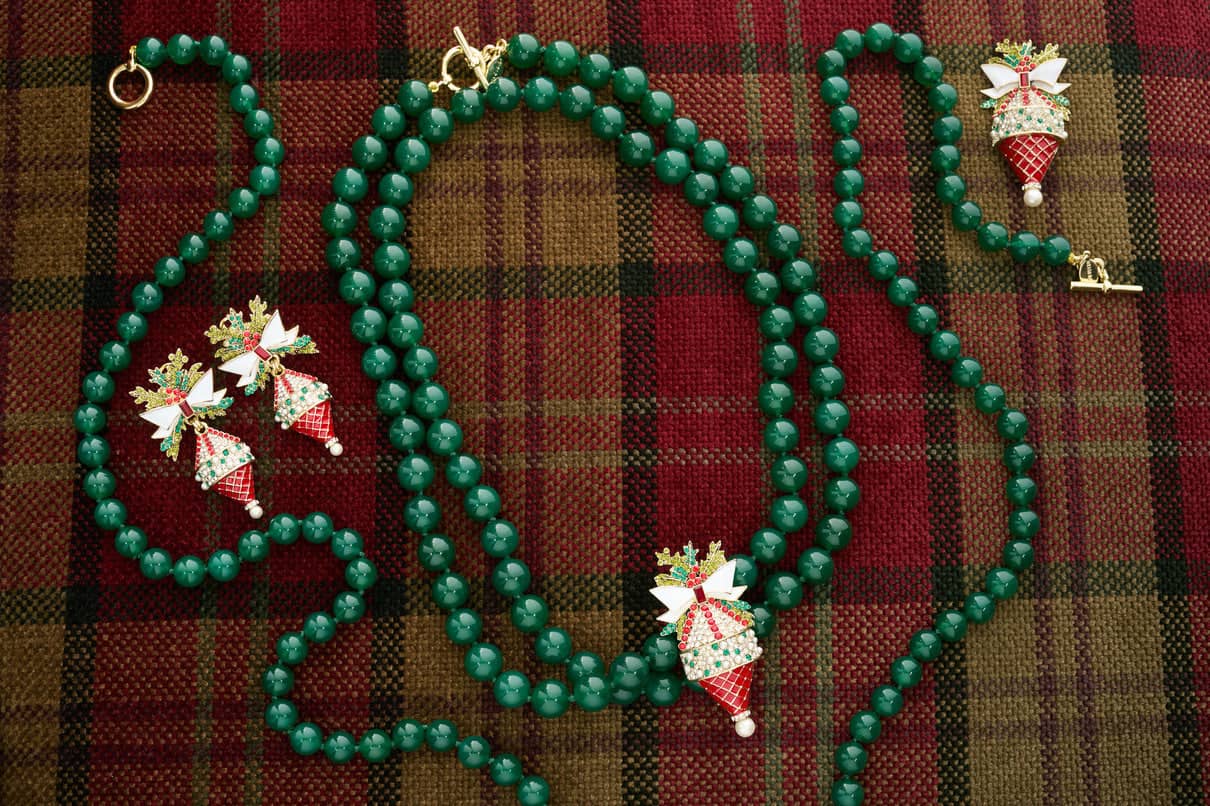 Green beaded necklace with festive pendant on a plaid fabric background