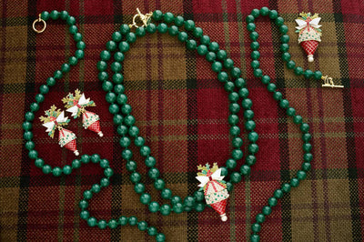 Green beaded necklace with festive pendant on a plaid fabric background