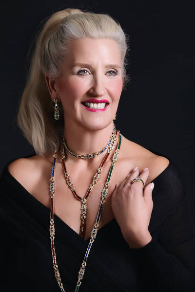 Woman wearing a long necklace against a black background