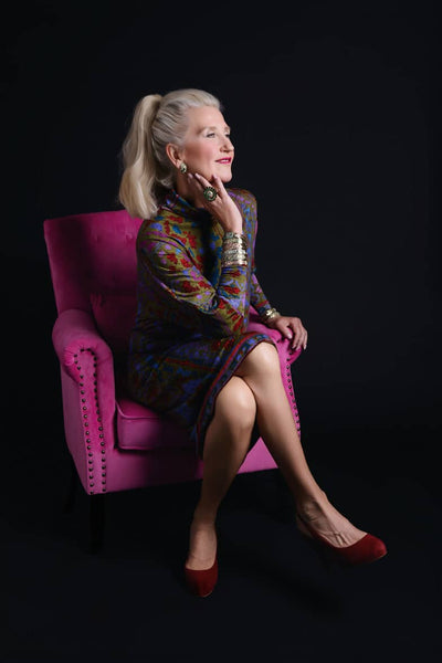 Woman sitting on a pink chair against a black background