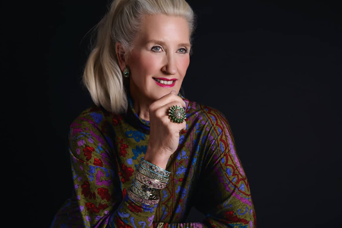 Woman wearing a colorful patterned top against a black background