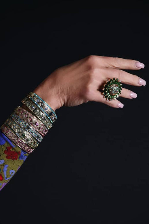 Hand with decorative ring and colorful sleeve against a black background