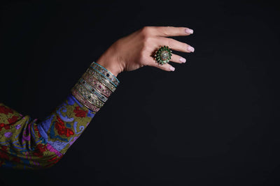 Hand with colorful bangles and a ring on a black background