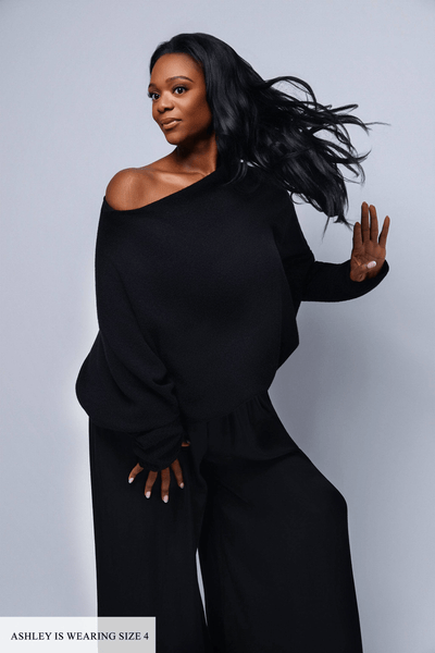 Woman wearing a black outfit against a gray background