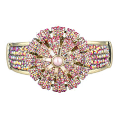 A wide gold-plated cuff bracelet featuring a large, symmetrical flowerburst design paved with pink and iridescent rhinestones, with a central pink stone.