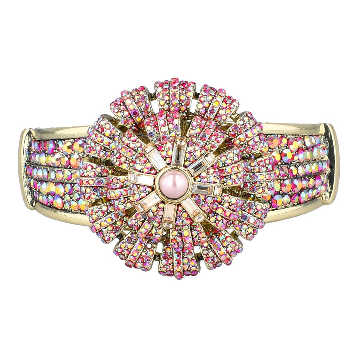 A wide gold-plated cuff bracelet featuring a large, symmetrical flowerburst design paved with pink and iridescent rhinestones, with a central pink stone.