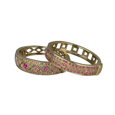 Two gold bangles with pink gemstones on a white background. daily double bracelet set by heidi daus