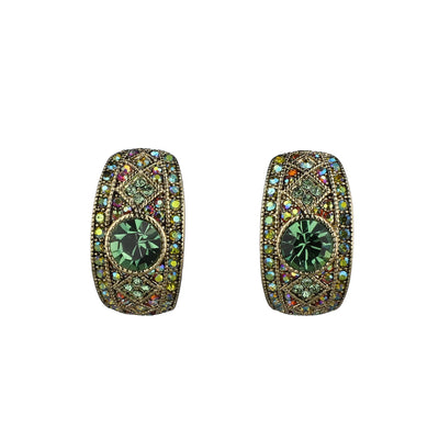 Pair of ornate earrings with green gemstones on a white background