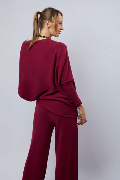 Woman wearing a burgundy outfit against a plain background