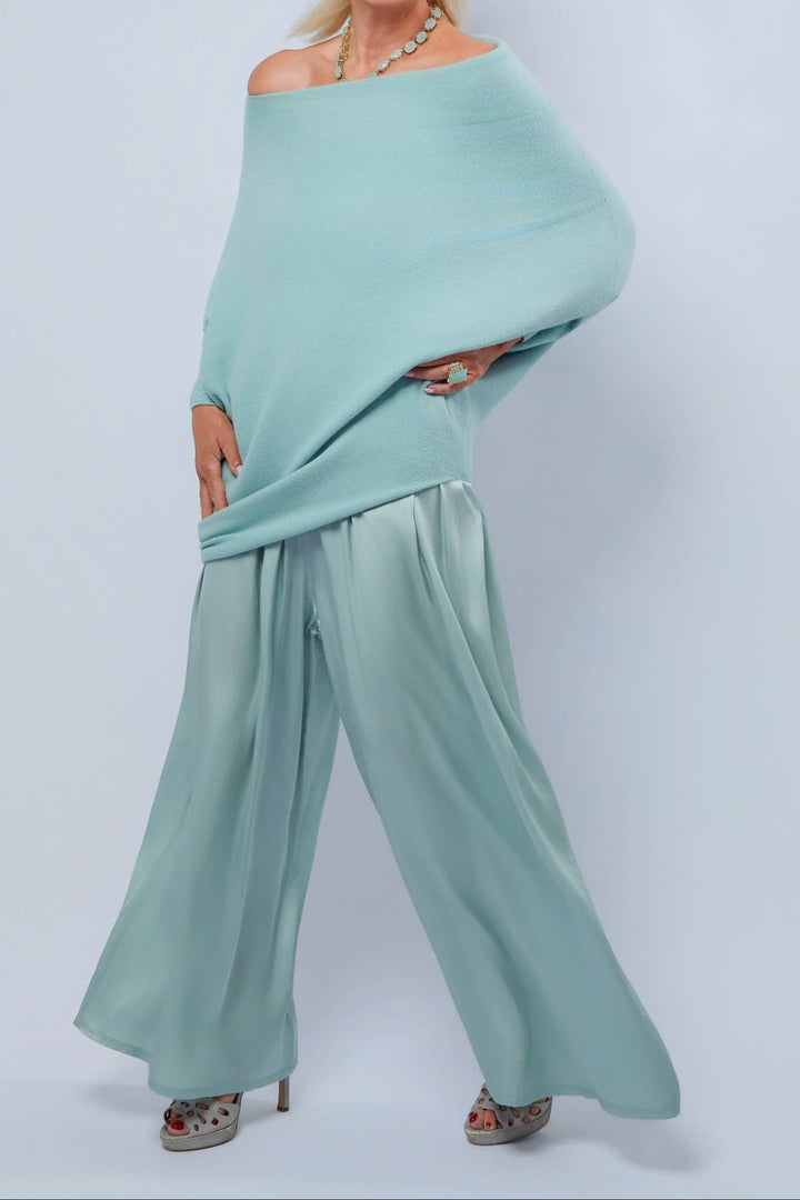Woman wearing a light blue off-shoulder top and wide-leg pants on a white background