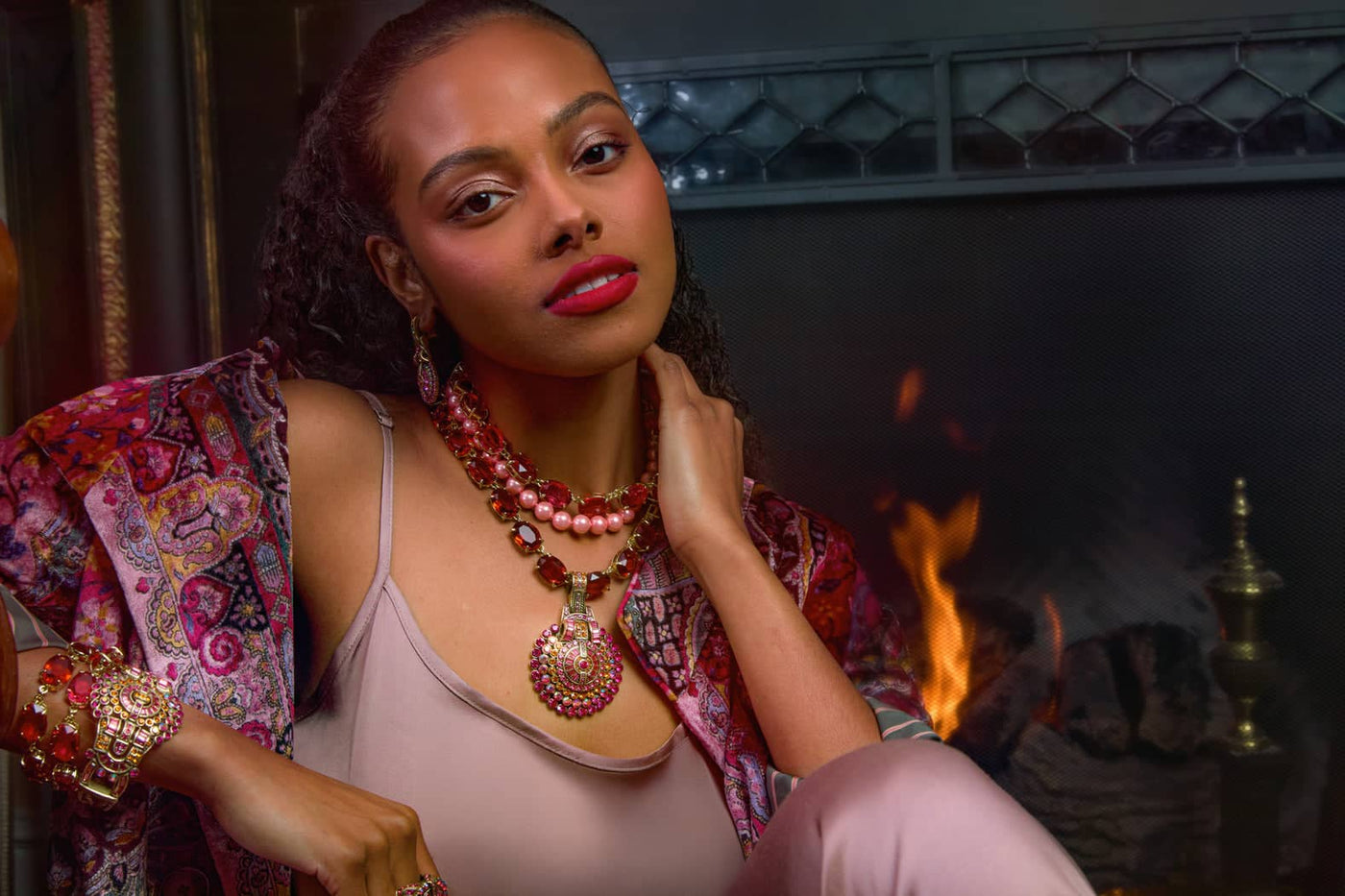 Woman wearing a colorful outfit with jewelry in front of a fireplace