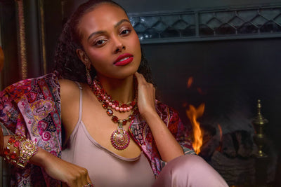 Woman wearing a colorful outfit with jewelry in front of a fireplace