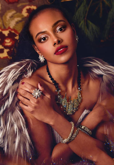Woman in elaborate costume with feathers and jewelry against a patterned background