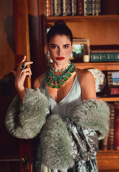 Woman wearing a green necklace in a room with bookshelves