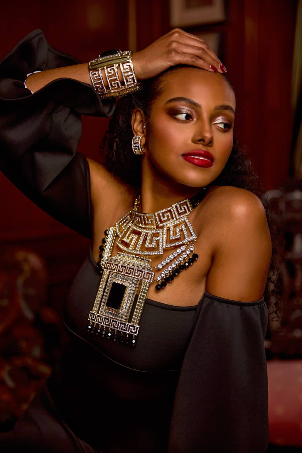 Woman wearing a black outfit with gold jewelry against a blurred background