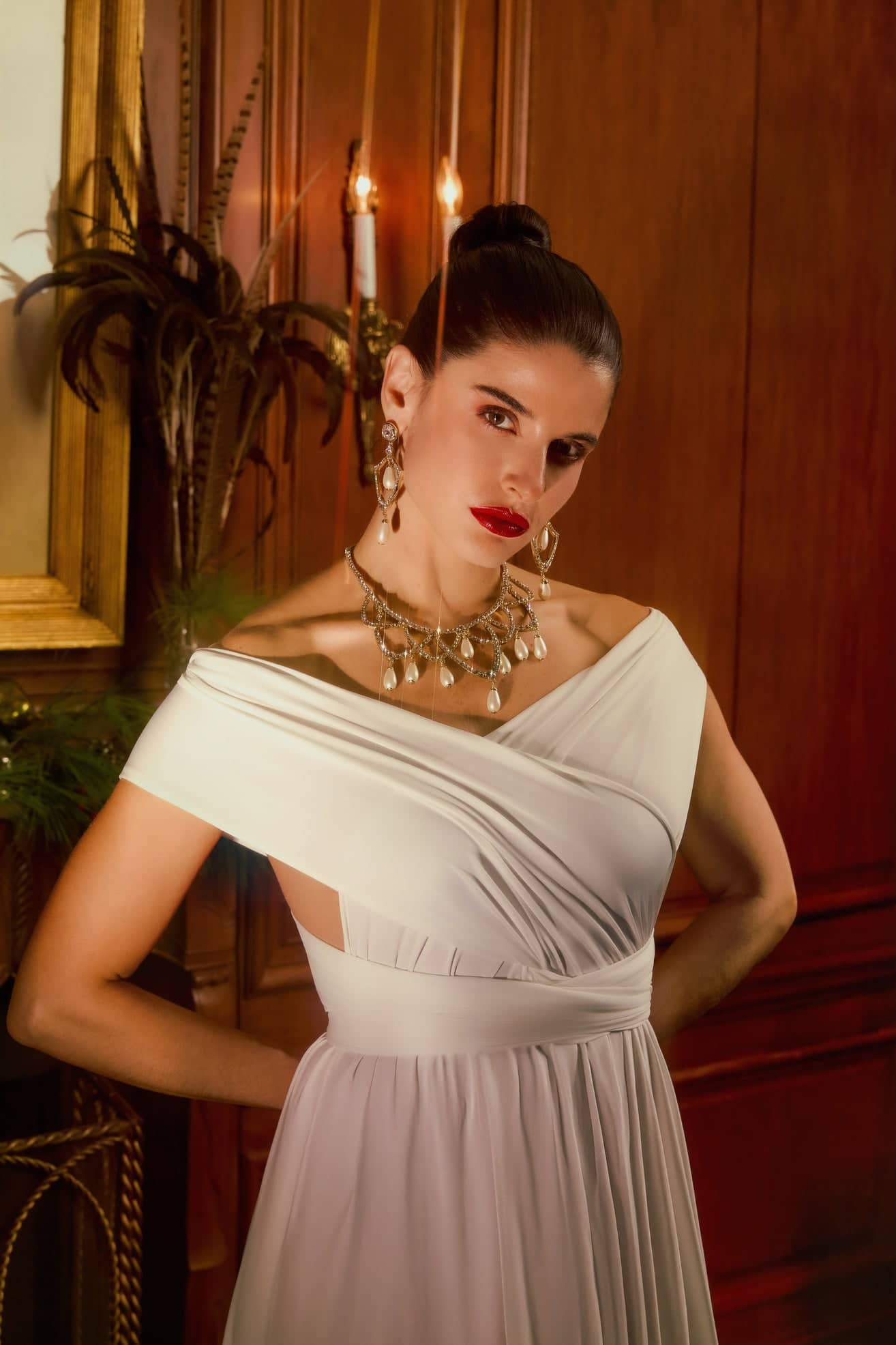 Woman in a white off-shoulder dress posing in an elegant indoor setting.