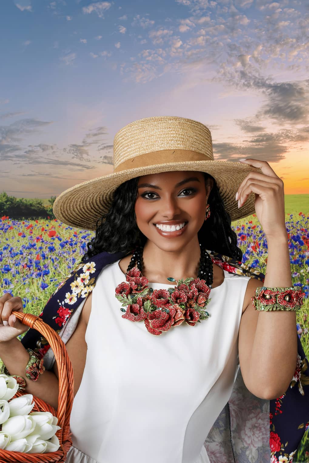 Woman in a white dress and straw hat holding a basket of flowers in a field with a sunset.