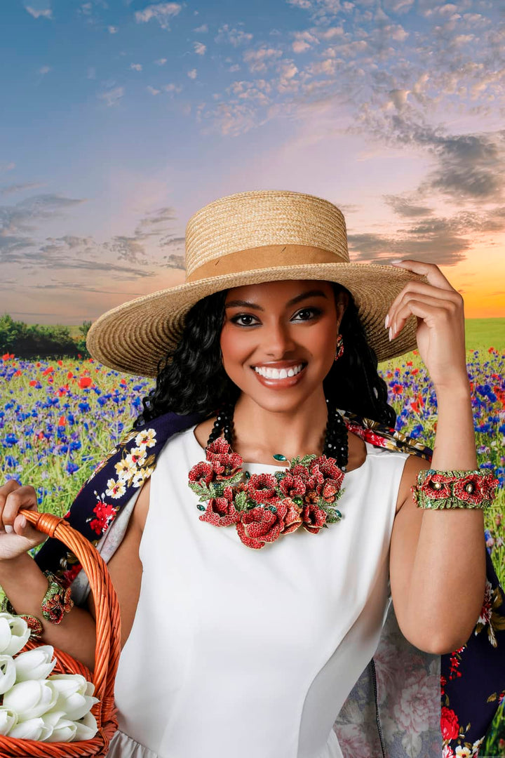 Woman in a white dress and straw hat holding a basket of flowers in a field with a sunset.