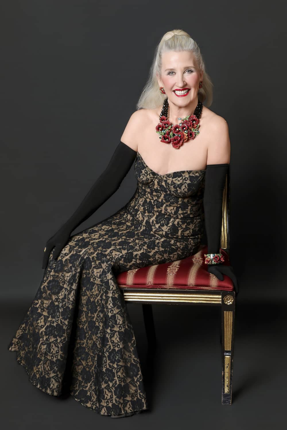 Woman in a patterned dress sitting on a chair with a dark background