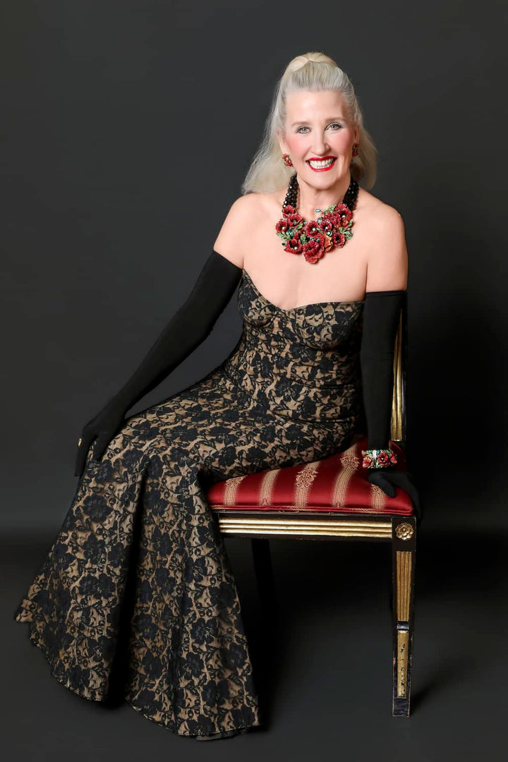 Woman in a patterned dress sitting on a chair with a dark background