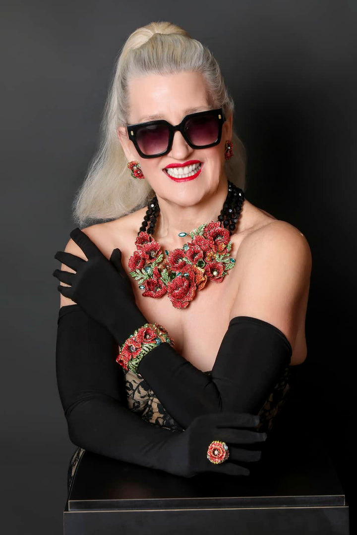 Woman wearing a floral necklace and black gloves against a dark background