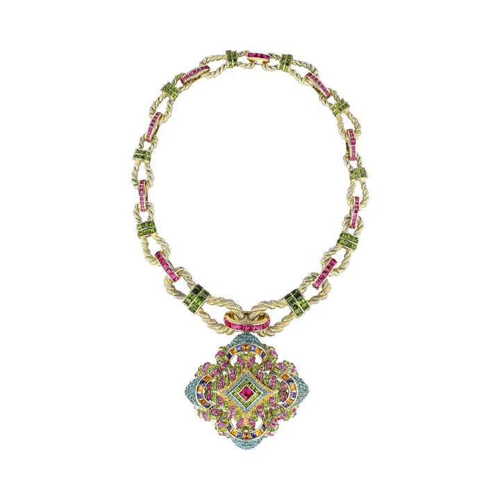 An ornate gold-toned necklace with a large decorative pendant, featuring green and pink gemstone accents along the chain and a multicolored floral medallion pendant.