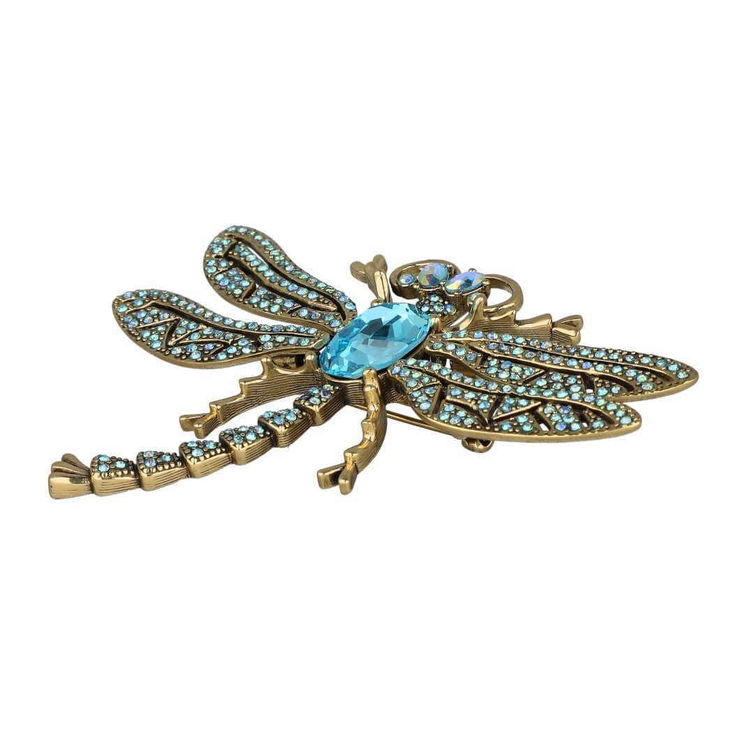 Decorative dragonfly brooch with turquoise gemstones on a white background
