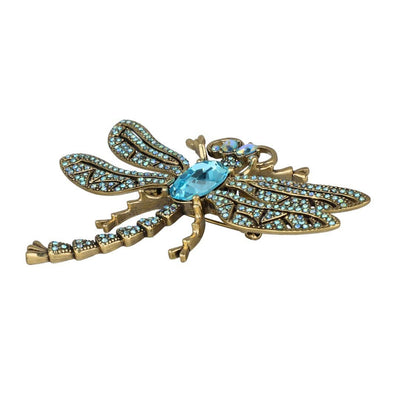 Decorative dragonfly brooch with turquoise gemstones on a white background