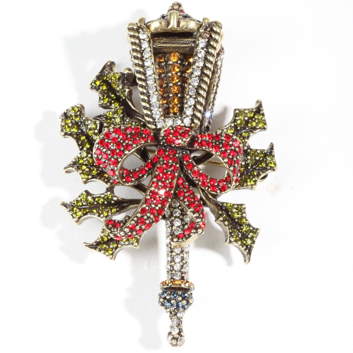 Decorative brooch with red bow and green leaves on a white background