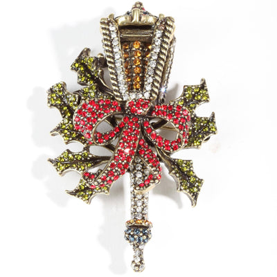 Decorative brooch with red bow and green leaves on a white background