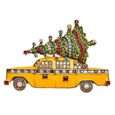 Decorative brooch shaped like a yellow taxi with a Christmas tree on top, featuring colorful gemstones.