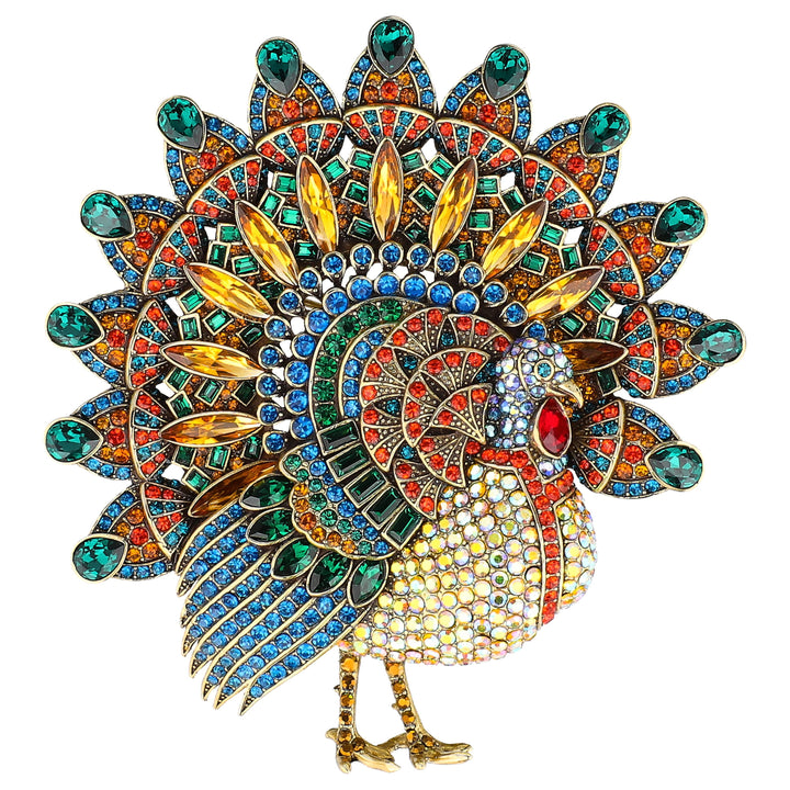 A highly detailed, colorful peacock brooch featuring gold metalwork, green, blue, red, and yellow rhinestones, and enamel detailing, set against a plain white background.