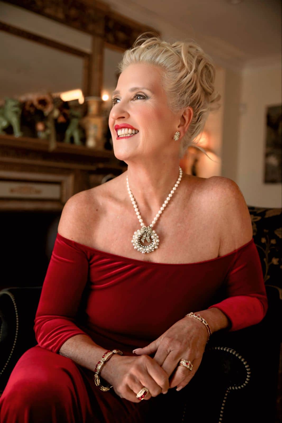 Woman in a red dress with jewelry sitting in a room.