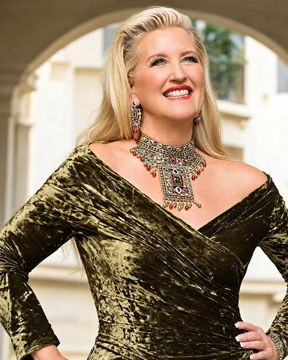 Heidi Daus wearing an olive velvet dress with a statement crystal necklace and earrings.